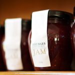 Small glass jars filled with ruby-red rhubarb jam on a rustic wooden surface